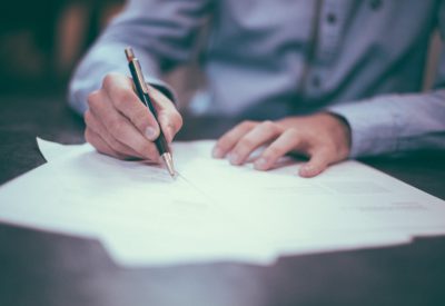 Man with pen writing on paper documents; highlighting proposed tax changes